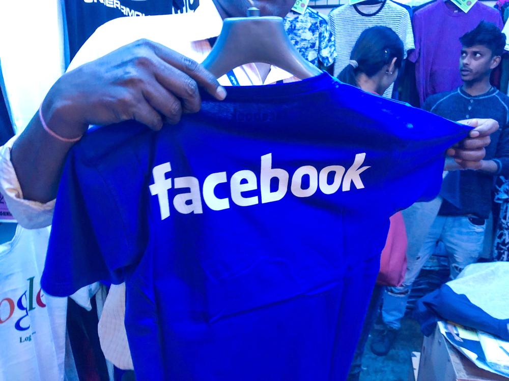 An Indian man looks at imitation Facebook T Shirts inside a shop in New Delhi on Wednesday. — AFP