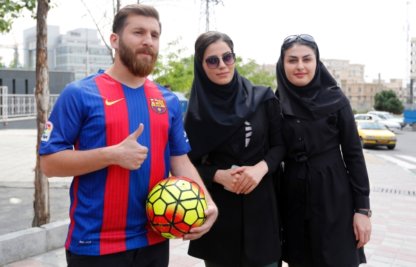 Reza Parastesh, a doppelganger of Barcelona and Argentina's footballer Lionel Messi, poses for a picture with fans in a street in Tehran on Monday. — AFP
