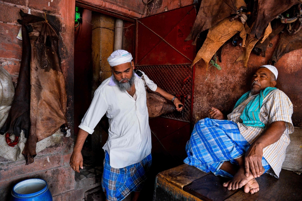 Indian water carrier Shakeel Ahmad leaves a shrine as he prepares to sell water from a goat skin canteen near Jama Masjid in New Delhi. Shakeel Ahmad wanders the cramped alleyways of Old Delhi offering water from a goat hide canteen slung over his shoulder, a centuries-old service welcomed by thirsty vendors toiling under the baking Indian sun. — AFP