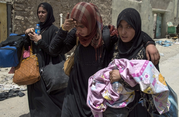 Iraqi women carry their belongings as they flee the Old City of Mosul during the government forces' ongoing offensive to retake the city from the Daesh group. — AFP