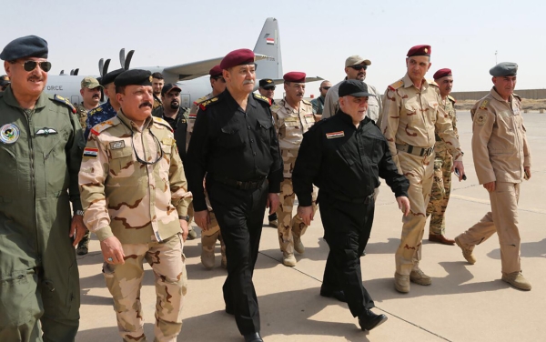 A handout picture released by the Iraqi prime minister’s press office on Sunday shows Iraqi Prime Minister Haider Al-Abadi (3rd from R) walking alongside police and army officers upon his arrival in Mosul. Abadi declared victory in the “liberated” city of Mosul, his office said, after a grueling nearly nine-month battle against the Daesh group. — AFP