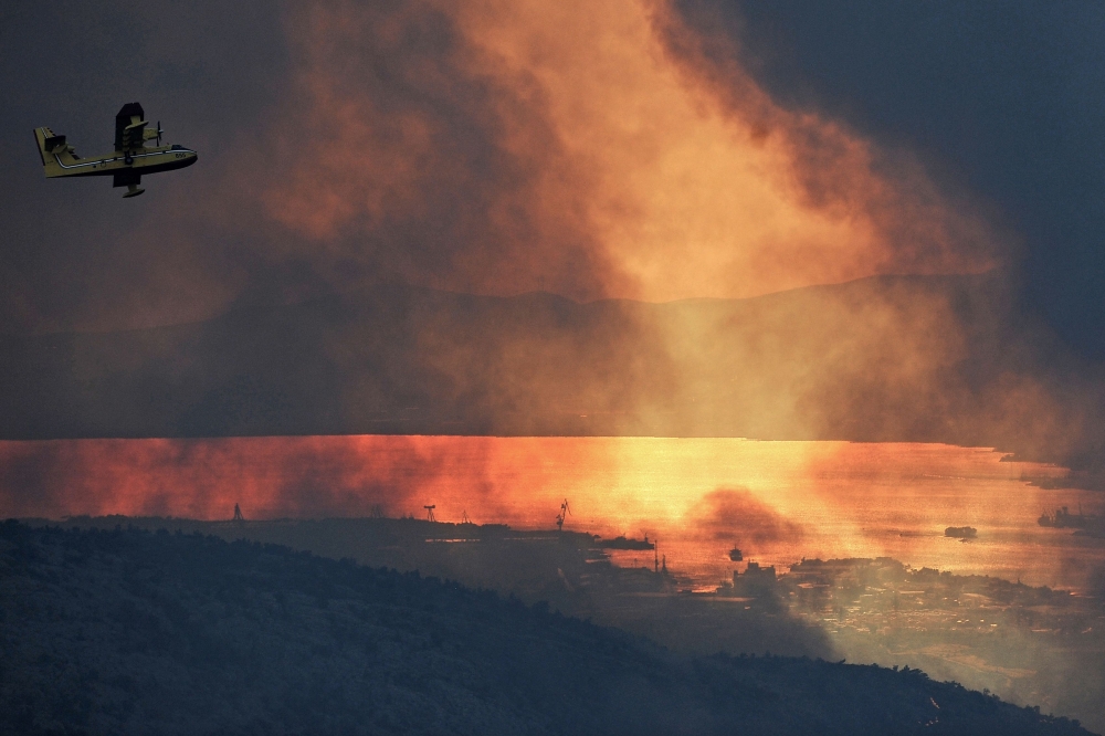 A Canadair of the Croatian Air Force flies over the village of Gornje Sitno, near the Adriatic coastal town of Split, Croatia, during a fire on Monday. — AFP