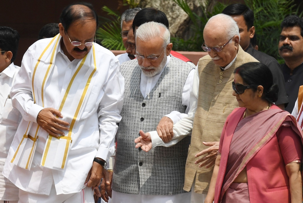 Indian Prime Minister Narendra Modi, second left, talks with Bhartiya Janata Party (BJP) leader Venkaiah Naidu, left, and senior leader L. K. Advani, second right, as they arrive to file their nomination papers for the forthcoming vice presidential election at Parliament in New Delhi on Tuesday. — AFP