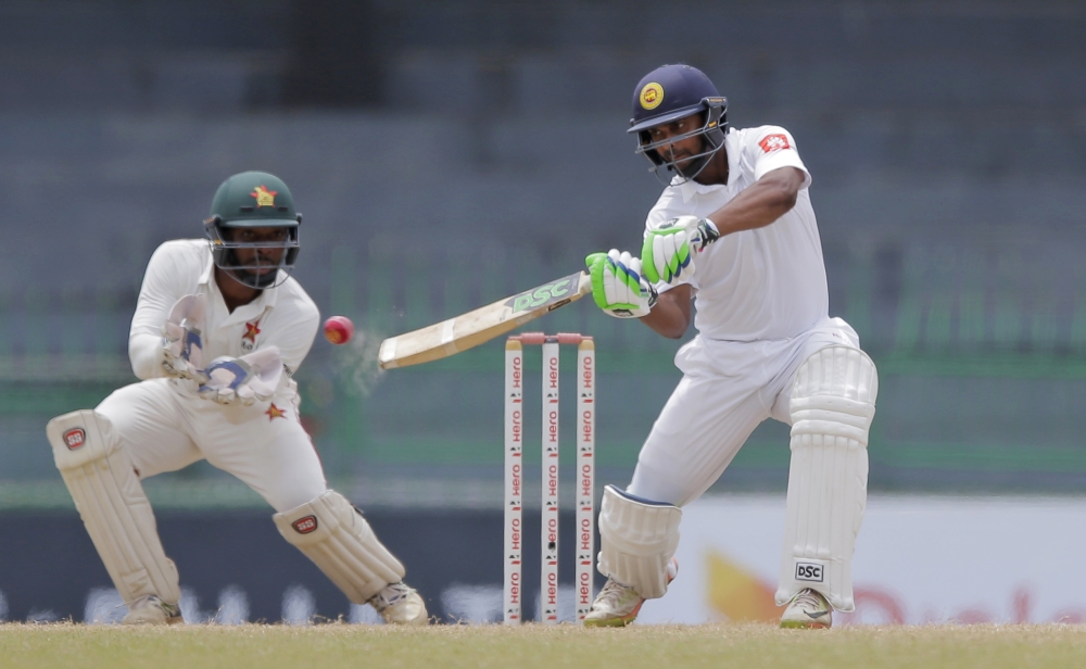 Sri Lanka's Asela Gunaratne plays a shot as Zimbabwe's Regis Chakabva watches during the final day of the only test cricket match between Sri Lanka and Zimbabwe in Colombo, Sri Lanka, Tuesday, July 18, 2017. (AP Photo/Eranga Jayawardena)
