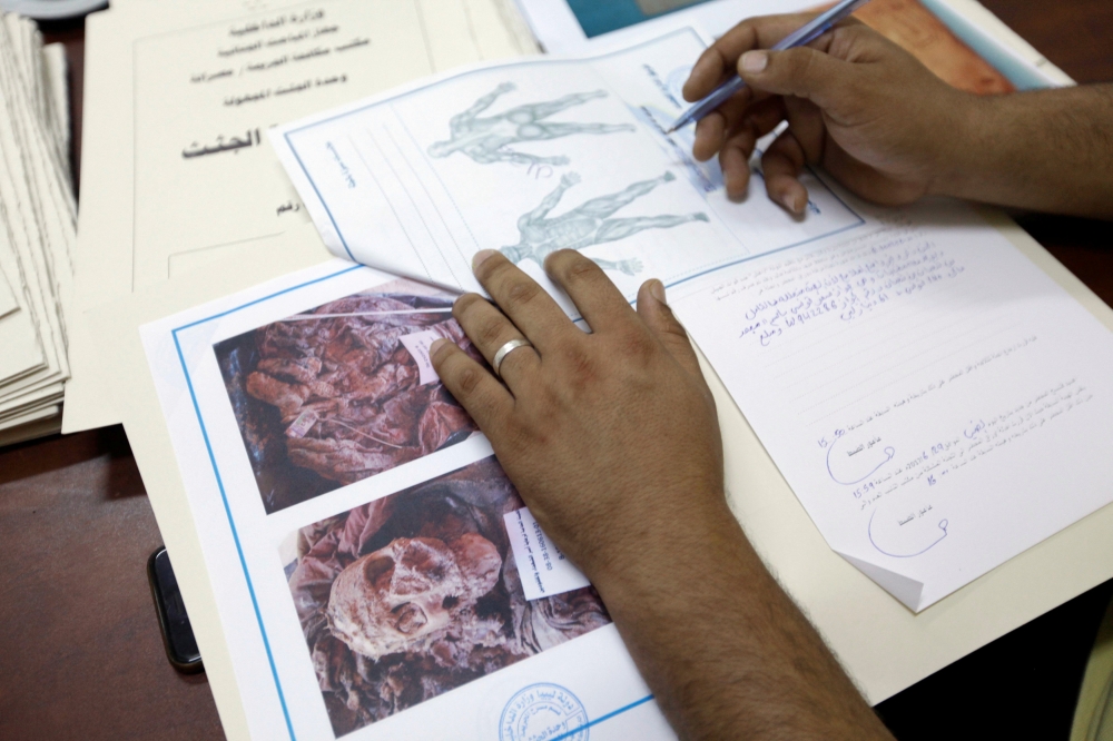A member of Libyan anti-crime service shows documents with details on dead bodies of Daesh militants held in a morgue, in Misrata, Libya. — Reuters