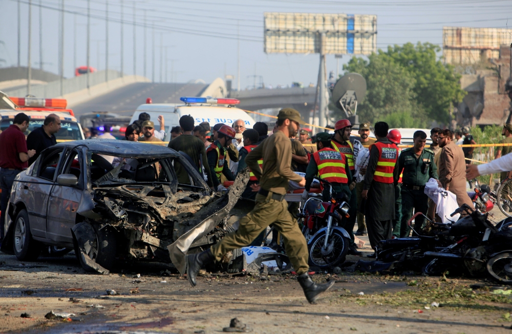 Rescue workers and policemen gather after a suicide blast in Lahore, Pakistan, on Monday. — Reuters