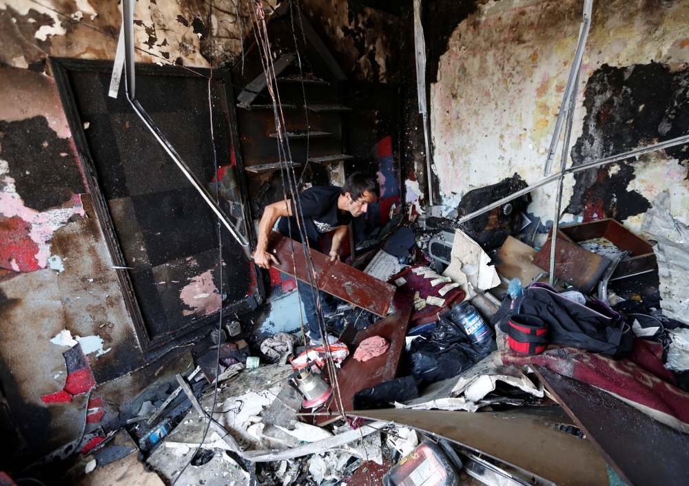 An Afghan shopkeeper inspects his shop after a suicide attack in Kabul on Monday. — Reuters