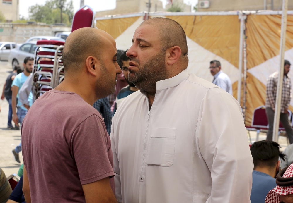 Zakariya Al-Jawawdah, right, the father of Mohammed Jawawdah, a 17-year-old Jordanian, who was killed on Sunday evening by an Israeli security guard who said he was attacked by him with a screwdriver, holds back his tears at a funeral tent in Amman, Jordan, Monday. — AP