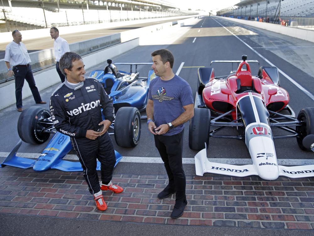 Two-time Indianapolis 500 winner Juan Pablo Montoya (L) and Spanish driver Oriol Servia talk in front of the newly-designed IndyCars at the Indianapolis Motor Speedway Tuesday. — AP 