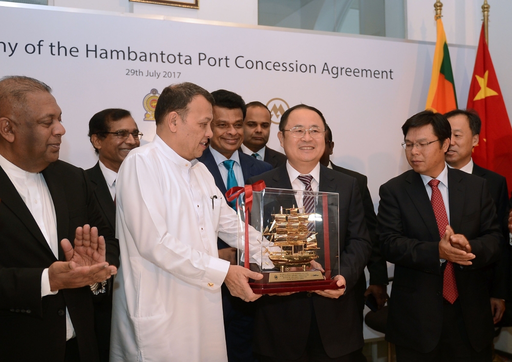 Sri Lanka's Minister of Ports & Shipping Mahinda Samarasinghe (C) exchanges souvenirs with Executive Vice President of China Merchants Port Holdings Dr. Hu Jianhua (3R) during the Hambantota International Port Concession Agreement at a signing ceremony in Colombo on July 29, 2017.  Sri Lanka entered into a billion-dollar deal with China on July 29 to revive a loss-making, but strategically-placed, harbor after addressing 
