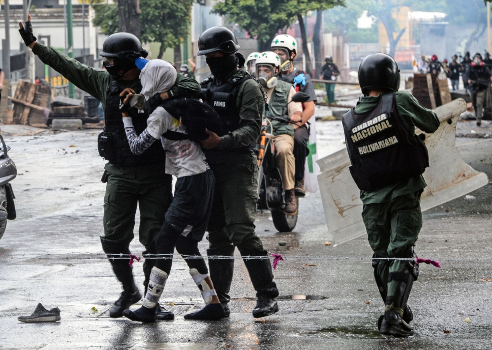An anti-government activist is arrested during clashes in Caracas on Friday. — AFP