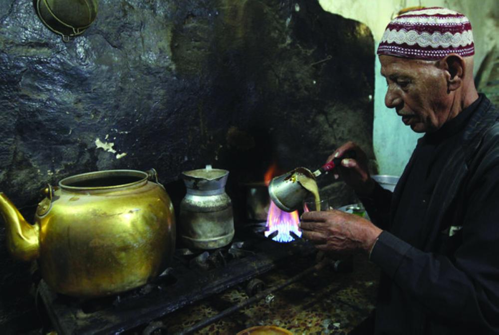 A vendor pours coffee into a cup for customers inside his cafe in the old city of Al-Masnaah in Al-Mahaweet, north west of Sanaa. — Courtesy photo 
