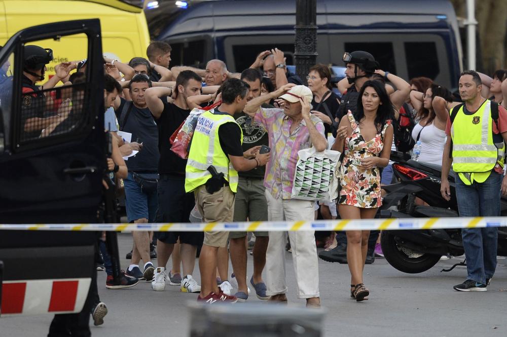 People leave a fastfood with hands up as asked by policemen after a van plowed into the crowd, killing two persons and injuring several others on the Rambla in Barcelona on Thursday. A driver deliberately rammed a van into a crowd on Barcelona's most popular street.  — AFP