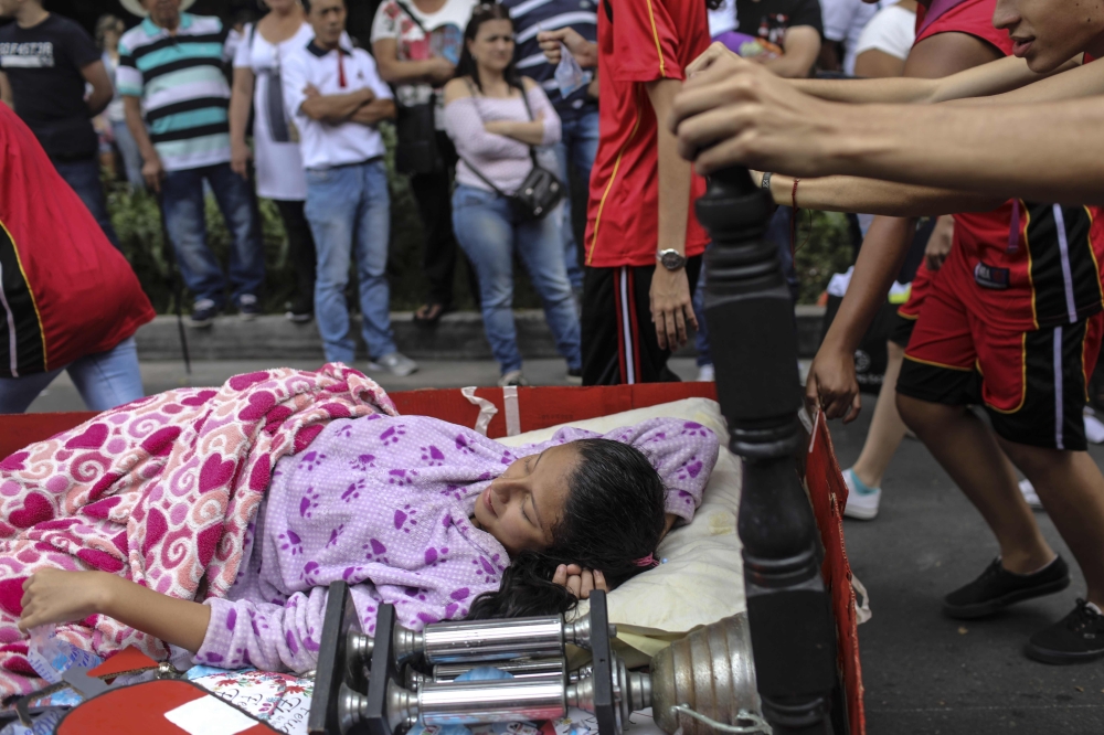 People gather to take photos of a woman taking part in a World Laziness Day parade in Itagui, near Medellin, Colombia, on Sunday. - AFP