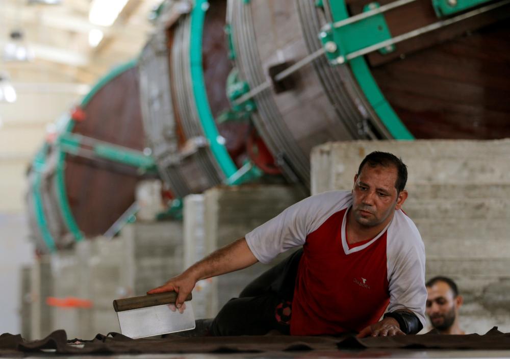 A worker removes impurities on leather in the factory of Al Rowad Leather Tannery at El Robbiki Leather City in Badr City, east of Cairo, Egyt. — Reuters