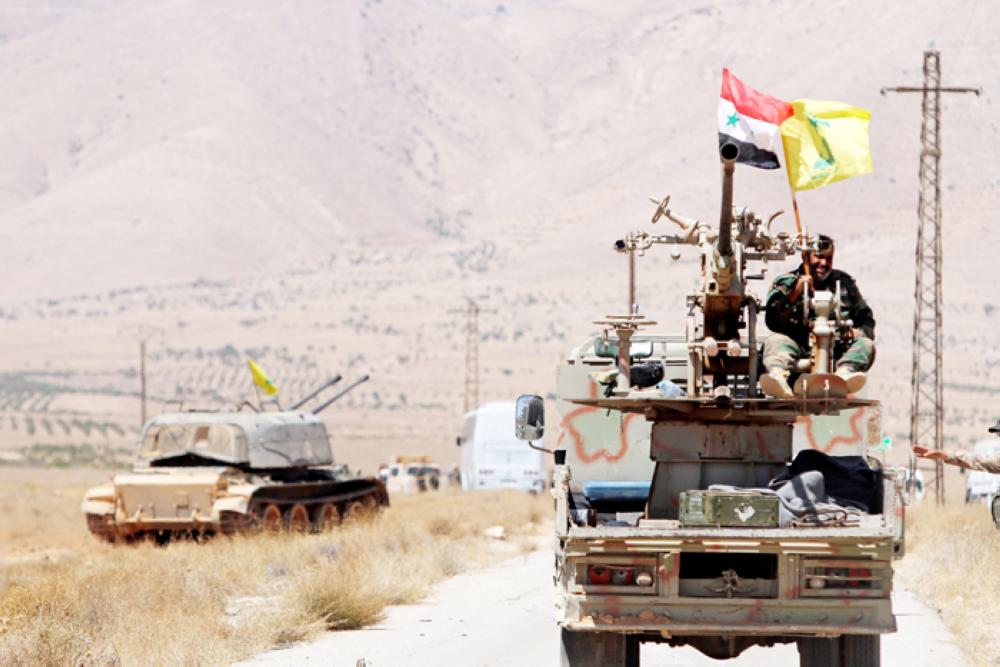 Hezbollah and Syrian flags flutter on a military vehicle in Western Qalamoun in Syria, Monday. — Reuters 
