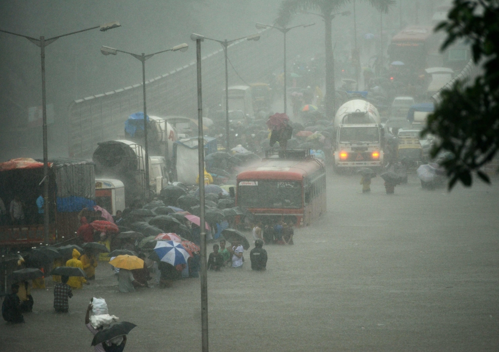 People wade along a flooded street during heavy rain showers in Mumbai on Tuesday. Heavy rain brought India's financial capital Mumbai to a virtual standstill, flooding streets, causing transport chaos and prompting warnings to stay indoors. Dozens of flights and local train services were canceled as rains lashed the coastal city of nearly 20 million people. —  AFP
