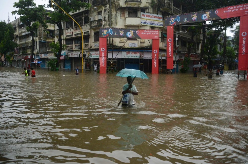 People wade along a flooded street during heavy rain showers in Mumbai on Tuesday. Heavy rain brought India's financial capital Mumbai to a virtual standstill, flooding streets, causing transport chaos and prompting warnings to stay indoors. Dozens of flights and local train services were canceled as rains lashed the coastal city of nearly 20 million people. —  AFP