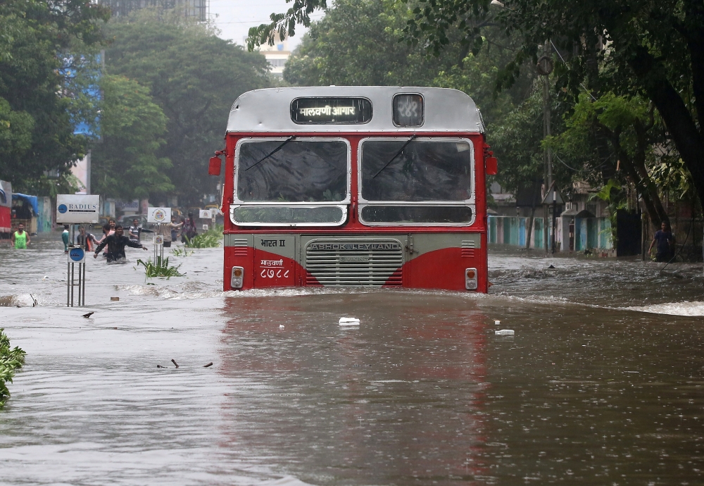 People wade along a flooded street during heavy rain showers in Mumbai on Tuesday. Heavy rain brought India's financial capital Mumbai to a virtual standstill, flooding streets, causing transport chaos and prompting warnings to stay indoors. Dozens of flights and local train services were canceled as rains lashed the coastal city of nearly 20 million people. —  AFP