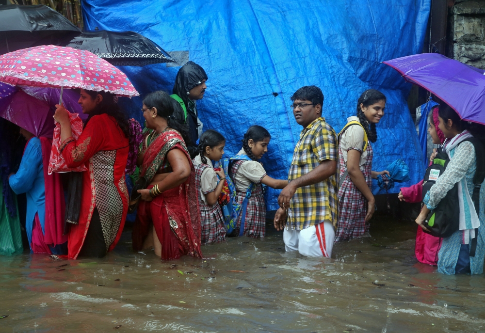 People wade along a flooded street during heavy rain showers in Mumbai on Tuesday. Heavy rain brought India's financial capital Mumbai to a virtual standstill, flooding streets, causing transport chaos and prompting warnings to stay indoors. Dozens of flights and local train services were canceled as rains lashed the coastal city of nearly 20 million people. —  AFP