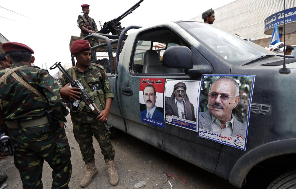 Yemeni security forces stand guard as Yemenis take part in a rally in support of Yemen's ex-president Ali Abdullah Saleh (portrait), as his political party marks 35 years since its founding, at Sabaeen Square in the capital Sanaa on Aug. 24.  With Saleh not leaving his home for a week, speculation is rife that he is under house arrest. — AFP