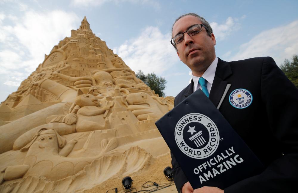 Jack Brockbank, the official judge of Guinness World Records stands next to the world's highest sandcastle (16.68 metres)  in Duisburg, western Germany Friday. — Reuters