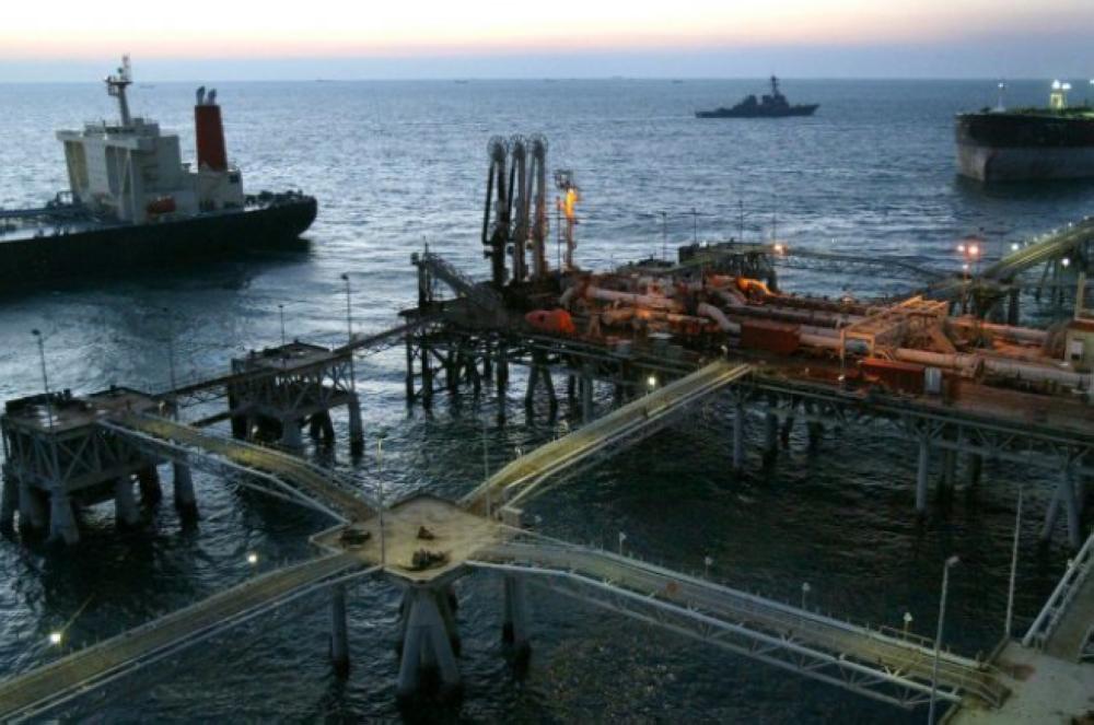 A tanker, left, leaves the Basra Oil Terminal as another tanker, top right, loads oil in The Gulf fifty kilometers south of Iraq. Photographer: Shawn Baldwin/Bloomberg News.