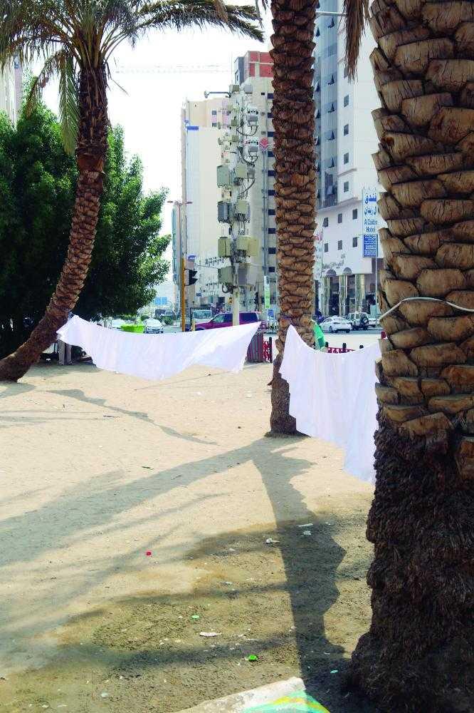 Picture shows pilgrims drying their shrouds by tying it to two trees after washing it with Zamzam water after completing their Haj. — courtesy photo