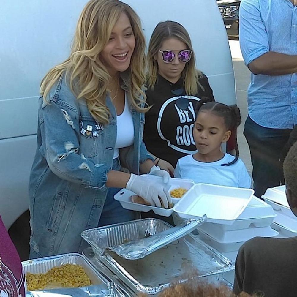 Singer Beyonce, left, is seen serving food at a food kitchen as her daughter, Blue Ivy, looks on in Houston, Texas on Saturday. 