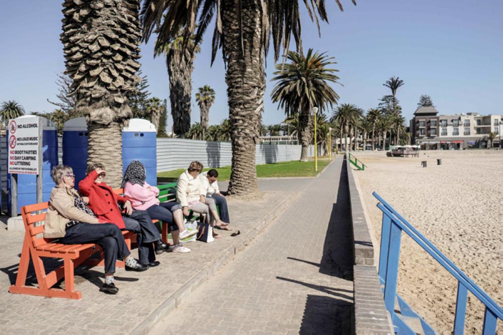 Tourists enjoy the sun as they sit on a bench on the Sea Promenade of Swakopmund.
