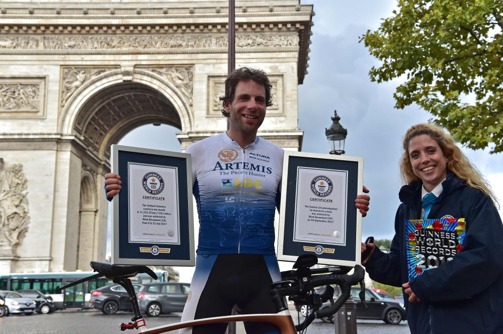 British cyclist Mark Beaumont poses for pictures with Guinness World Records certificates after arriving at the Arc de Triomphe in Paris on Tuesday to complete his tour around the world. - AFP