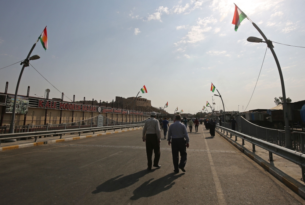 Iraqis walks down a street flying Kurdish flags in the mainly Kurdish Iraqi city of Kirkuk. — AFP