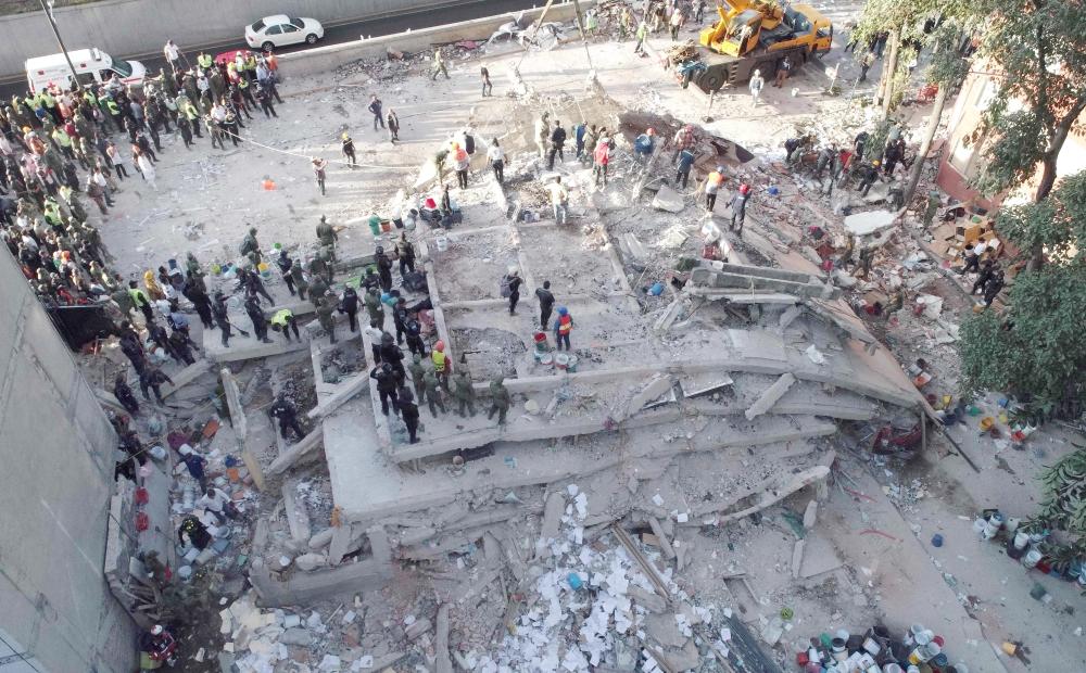 Rescuers look for survivors in a multistory building flattened by a powerful quake in Mexico City on Tuesday. — AFP