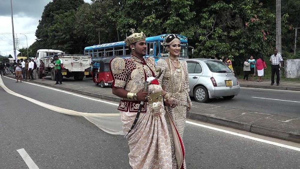 A Sri Lankan couple walk along a road as the bride attempted to set a record for the longest wedding saree extending 3.2 kilometers in the central district of Kandy on Friday. - AFP