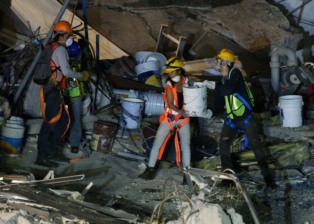 Members of rescue teams remove debris in the rubble of a collapsed building after an earthquake in Mexico City, Mexico, on Monday. — Reuters