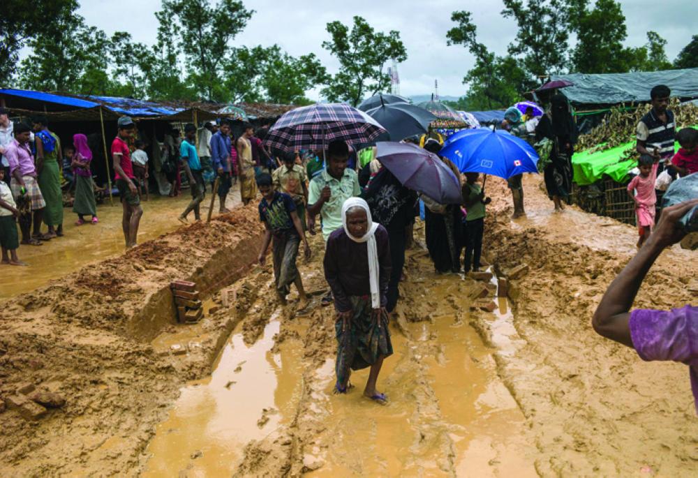 A Rohingya carries his elderly relative under the cover of darkness from Myanmar to Bangladesh. — Reuters
