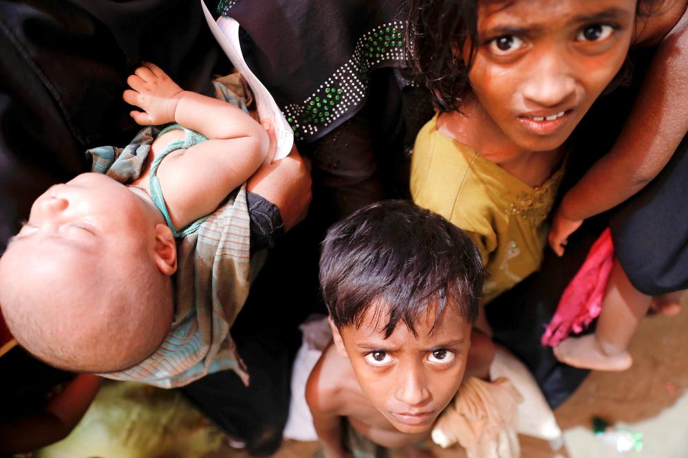 Rohingya refugees who just arrived by wooden boats from Myanmar wait for some aid to be distributed at a relief center in Teknaf, near Cox’s Bazar in Bangladesh on Tuesday. — Reuters