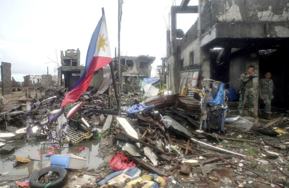 A Philippine flag is seen at destroyed houses in Bangolo town at Marawi city, southern Philippines, on Tuesday. — Reuters