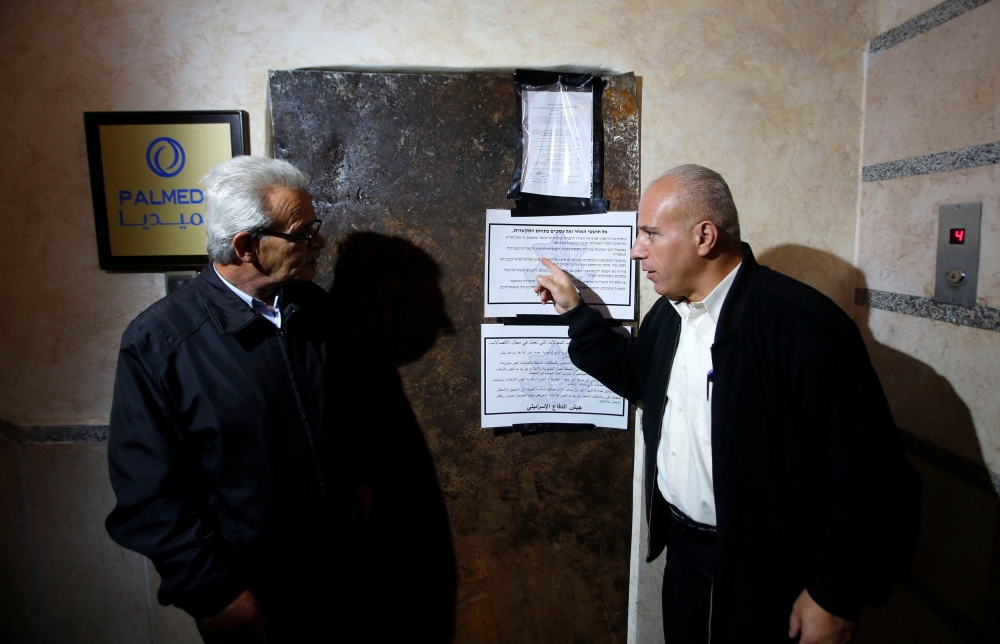 Palestinians check the entrance of Palmedia media production company after it was closed by the Israeli army in the West Bank city of Hebron, Wednesday. — Reuters