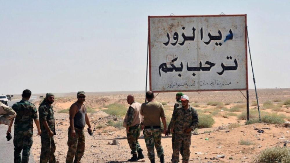 Gunmen stand next to a placard in Arabic that reads 'Deir Ezzor welcomes you,' in this file photo. — AP