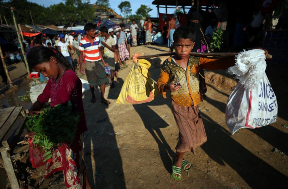 A Rohingya refugee carries supplies through Palong Khali refugees camp near Cox's Bazar, Bangladesh, Sunday. — Reuters