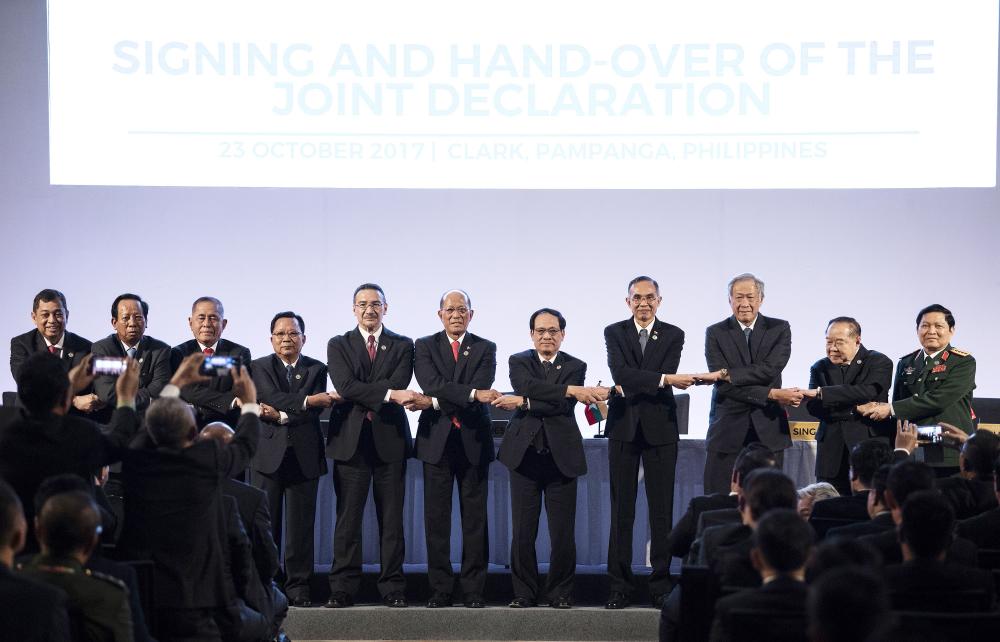 The Association of Southeast Asian Nations (ASEAN) Defence Ministers link arms during the signing and hand-over of the Joint Declaration on the sidelines of the 11th ASEAN Defense Ministers' Meeting (ADMM) opening ceremony in Clark, east of Manila on Monday. — AFP