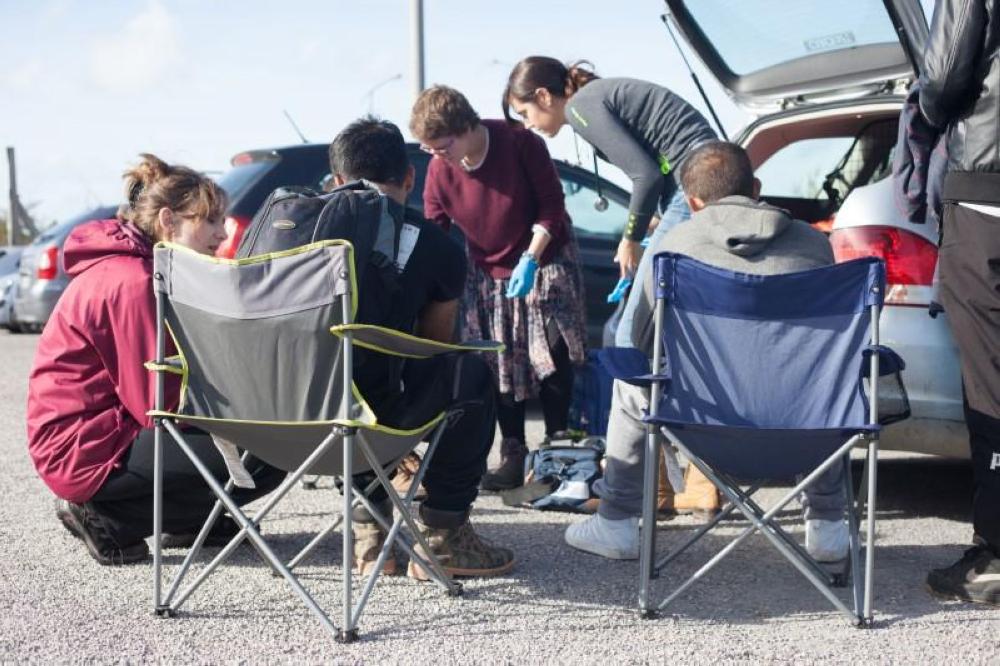 Volunteer doctors treat migrants who have minor injuries in a parking lot in Calais, France. - Thomson Reuters Foundation