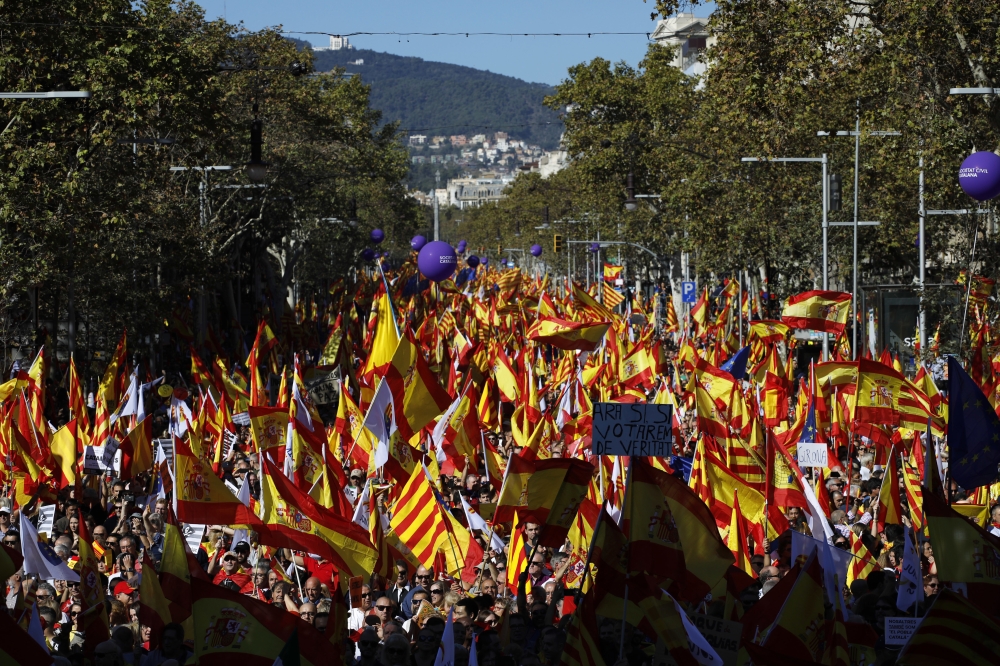 Nationalist activists march waving Catalan and Spanish flags during a mass rally against Catalonia's declaration of independence, in Barcelona, Spain, Sunday. Thousands of opponents of independence for Catalonia held the rally on one of the city's main avenues after one of the country's most tumultuous days in decades. — AP