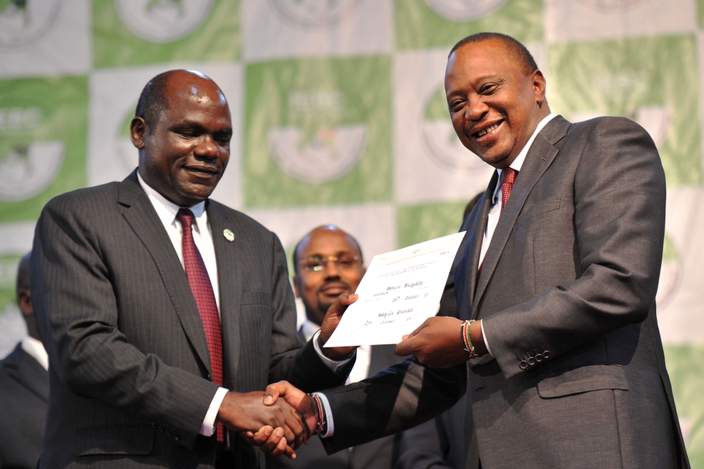Kenya's president-elect, Uhuru Kenyatta (R) holds his certificate of election on October 30, 2017 at the national tallying centre at Bomas of Kenya where they were announced winners of a repeat presidential poll by the Independent Electoral and Boundaries Commission chairman. Kenyan President Uhuru Kenyatta was declared victor of the country's deeply divisive elections on October 30, taking 98 percent of the ballots cast in a poll boycotted by his rival Raila Odinga, sparking fears of further violence in flashpoint opposition strongholds. / AFP / TONY KARUMBA
