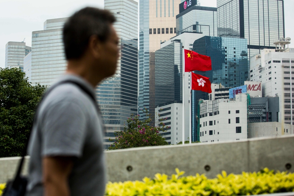 The Chinese and Hong Kong flags are seen outside the Legislative Council in Hong Kong on November 4, 2017.  China has passed a law to punish anyone who disrespects the national anthem, that law will also apply in Hong Kong the city's government said in a statement on November 4, once the authorities enact a local version of the legislation and get it passed through the legislature. / AFP / ISAAC LAWRENCE
