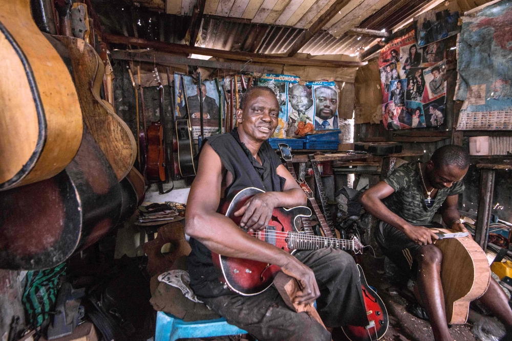 This file photograph taken on March 22, 2017, shows Misoko Nzalaya Jean Luther, alias Ir Socklo, a stringed-instrument maker for 40 years, as he poses with a guitar at his workshop in Kinshasa. - AFP