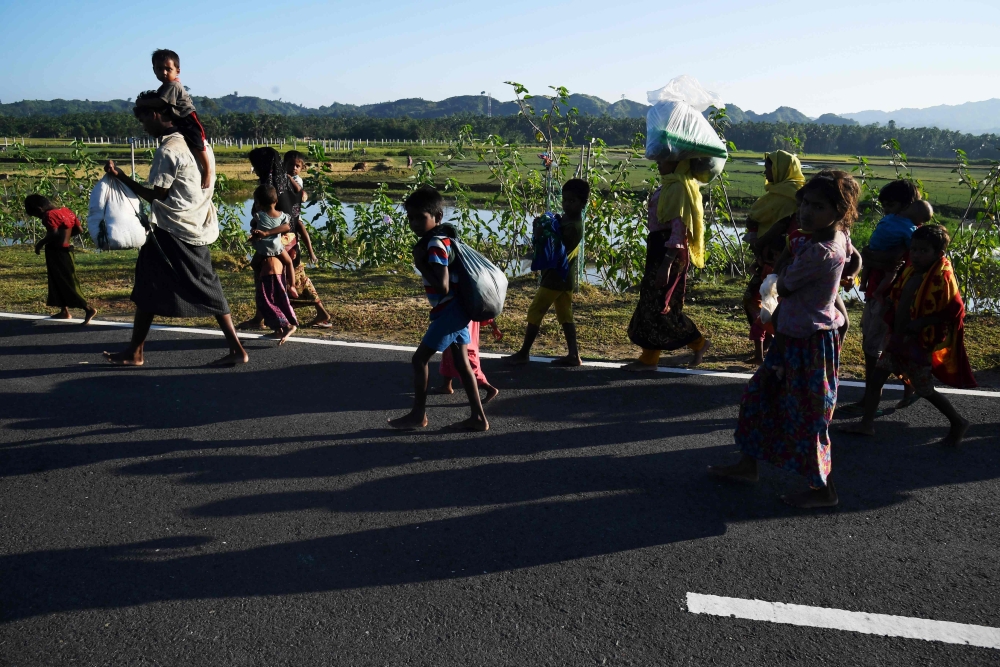 Rohingya refugees, who entered Bangladesh from Myanmar by boat, walk toward refugee camps in the Bangladeshi district of Teknaf, on Wednesday. — AFP