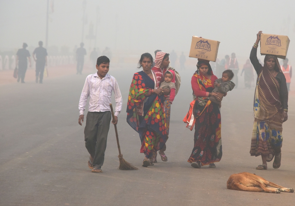 Residents walk along a road amid heavy smog in New Delhi, Thursday. Rickshaw driver Sanjay can only afford a handkerchief to shield his face as he weaves through the smog-filled streets of Delhi amid a rush on protection against the toxic menace. Better off residents of the global pollution black spot are swarming sellers of face masks — that cost more than the 300 rupees ($5) that Sanjay earns in a day — and high-tech air purifiers that could easily cost a year of his wage. — AFP