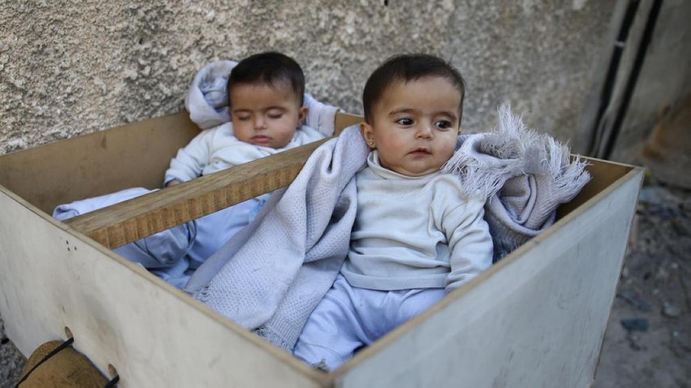 Five-month-old twins Farah and Marah wait for their parents to receive milk distributions from a medical center in the Hamoria area, in the eastern Damascus suburb of Ghouta, Syria. — Reuters